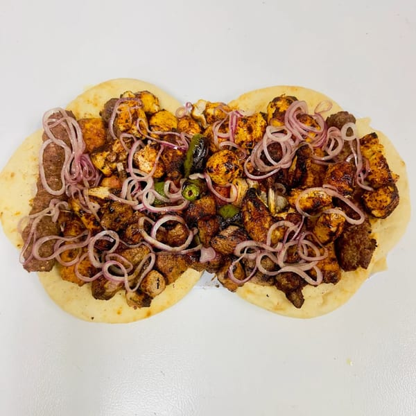 Halal chicken and beef kabobs with red onions and green peppers on flatbread.